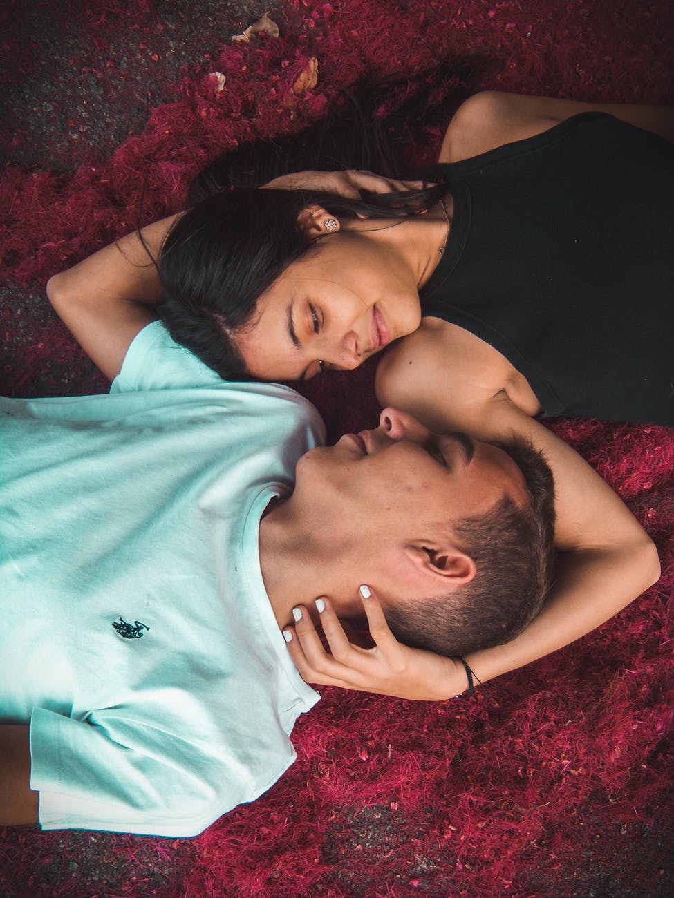 couple lying on ground while holding their hands