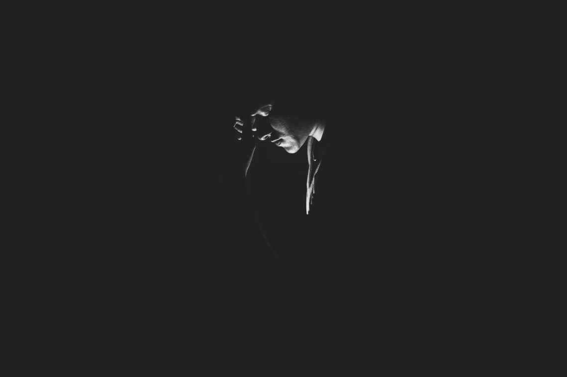 monochrome photography of person on dark room